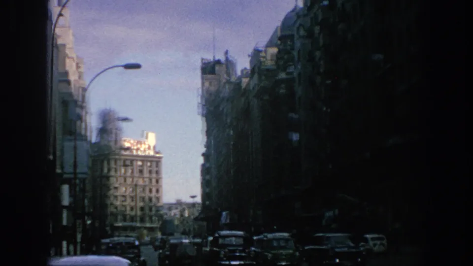 1966 Spain street view with classic cars below tall facades and a sunlit block beyond the avenue.