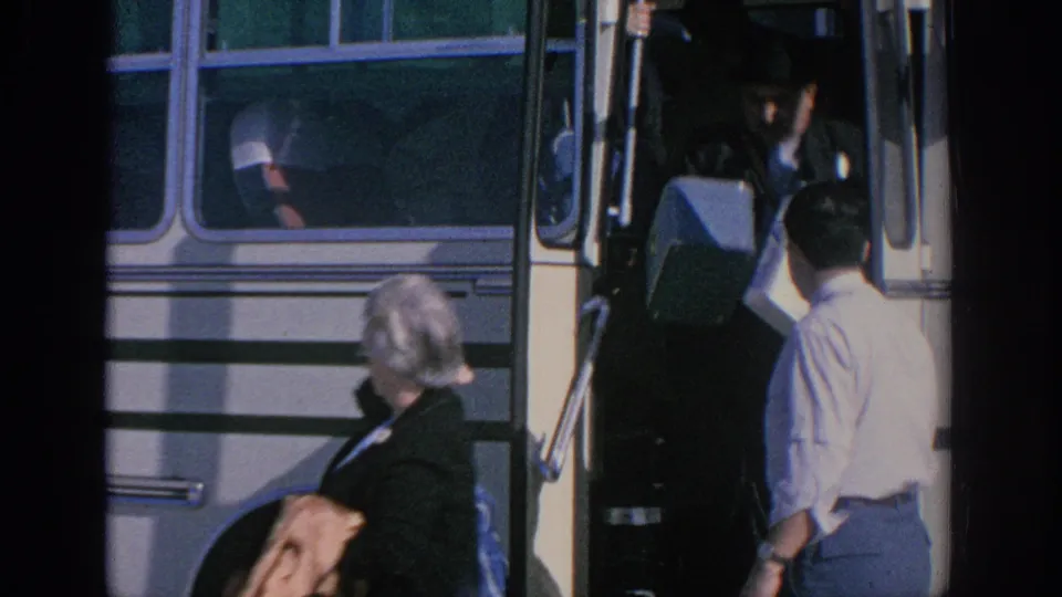 A person with a suitcase steps down from the bus while others stand nearby at the roadside stop in Spain in 1966.
