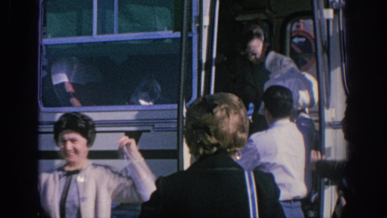 1966 Spain travel footage frame with a smiling woman near a white tour bus as passengers continue boarding or alighting.