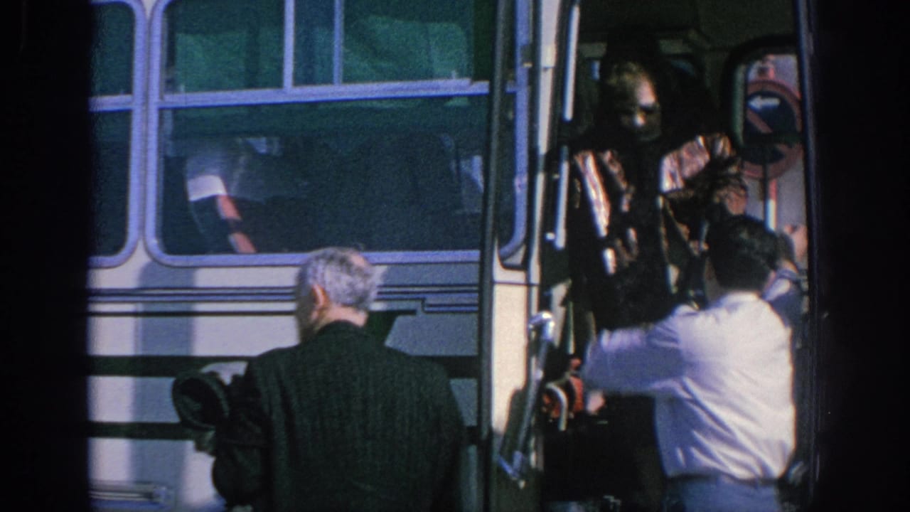 Spain 1966 home-movie frame showing adult passengers at a white bus doorway as a uniformed conductor assists boarding.