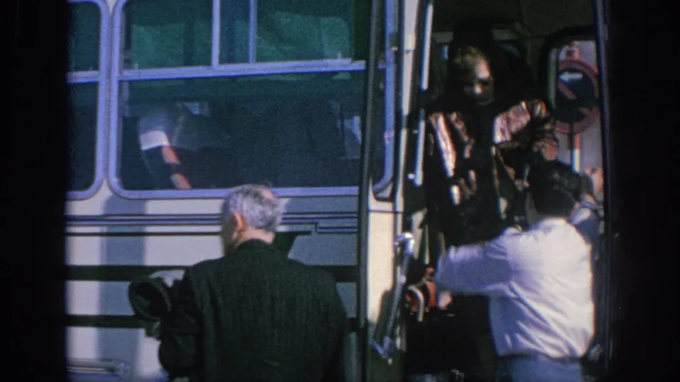 Spain 1966 home-movie frame showing adult passengers at a white bus doorway as a uniformed conductor assists boarding.