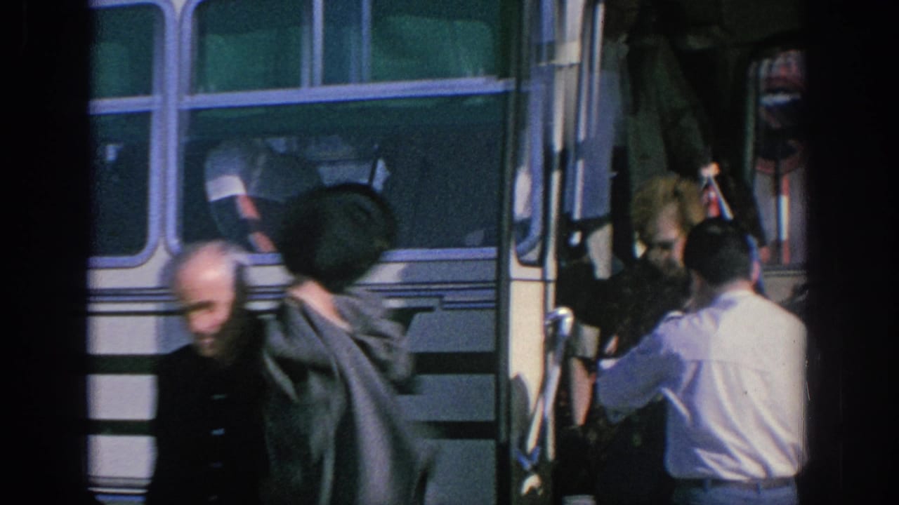 A passenger moves past the bus entrance as the conductor assists someone at the doorway.