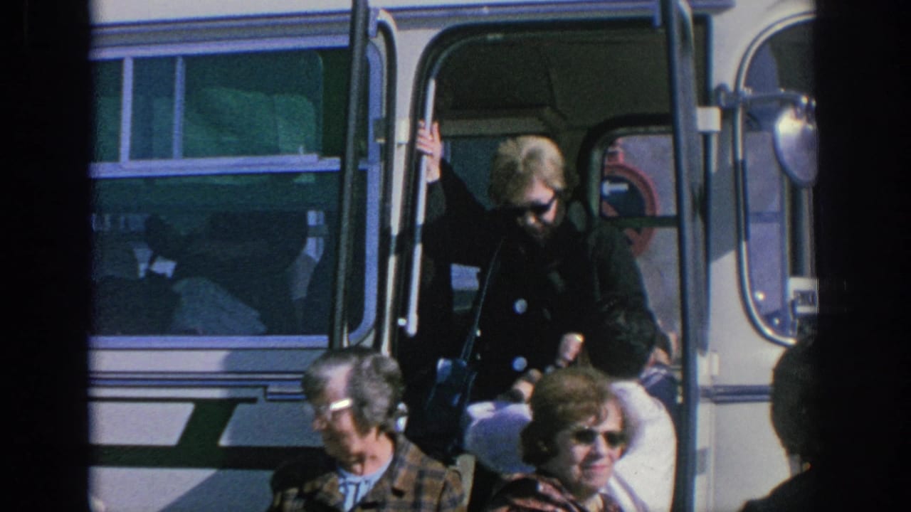 Spain 1966 frame of a woman in sunglasses and a dark coat disembarking from a tour bus as other adults stand nearby.