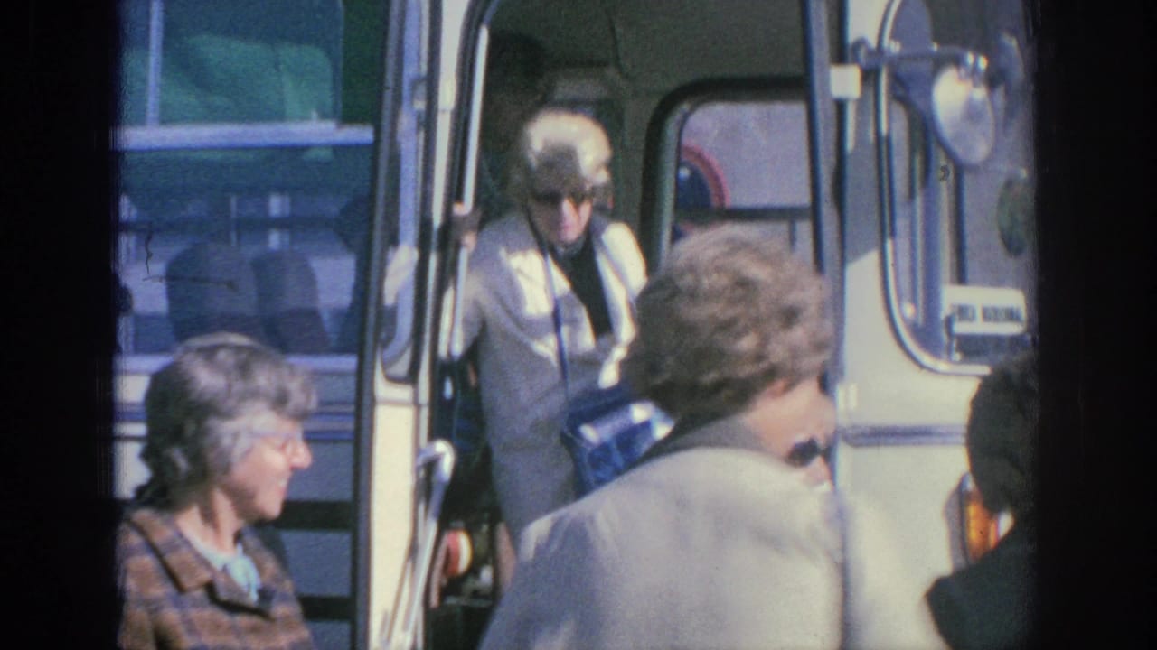 1966 Spain home-movie frame showing older women near an open white tour bus door, with one woman stepping from the bus.