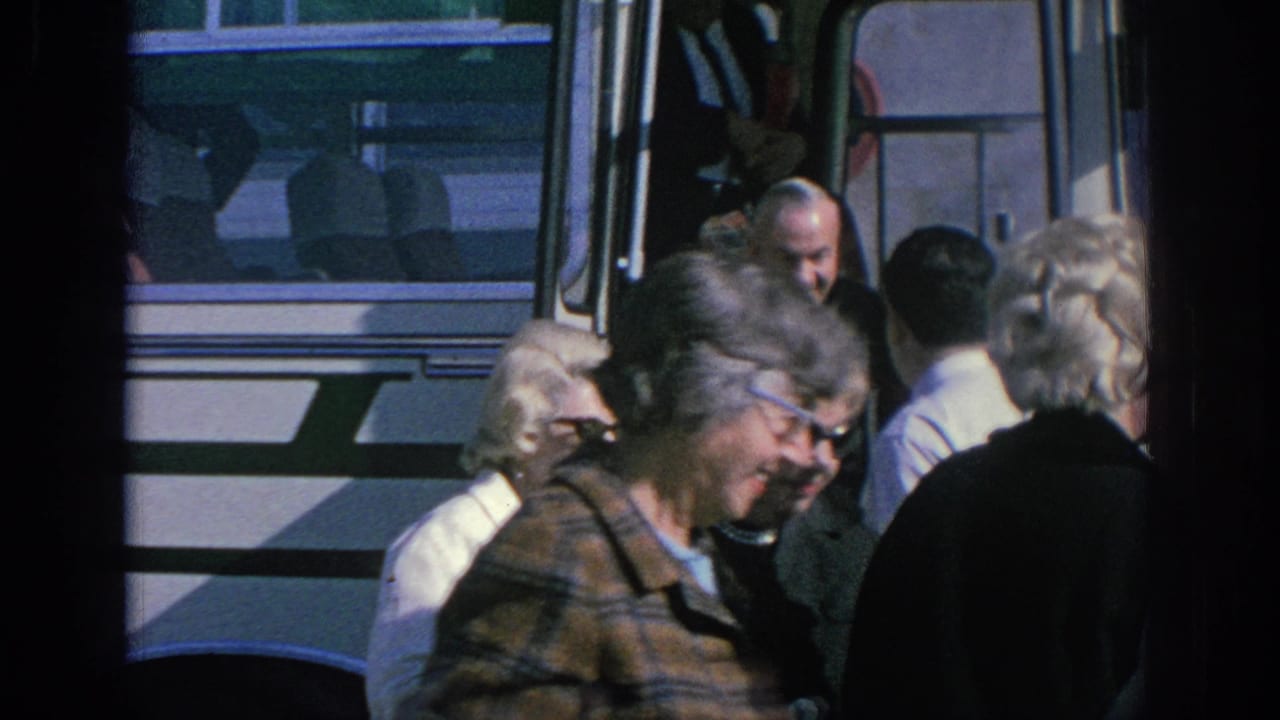 1966 Spain home-movie frame showing older adults clustered near the open doorway of a white bus.