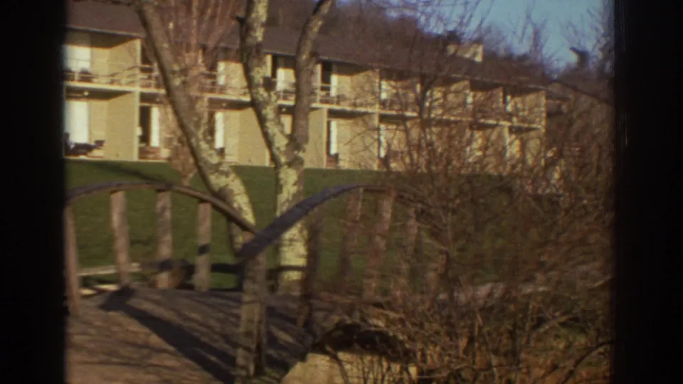 1971 Bedford, Virginia apartment buildings viewed through bare trees, with a wooden arched bridge in the foreground.