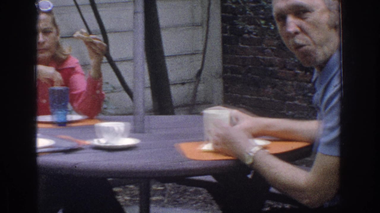 Adults seated at an outdoor table with cups and orange placemats.