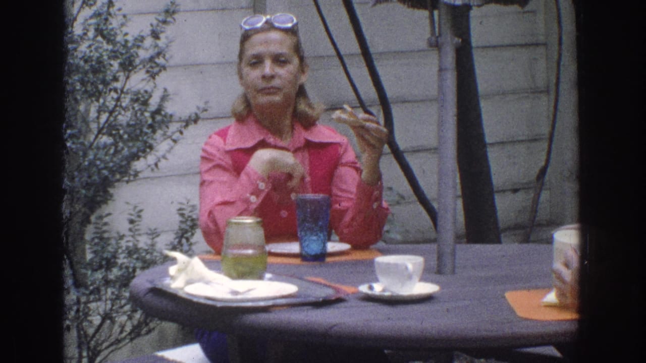 Woman in pink sits at an outdoor table with cups and dishes.