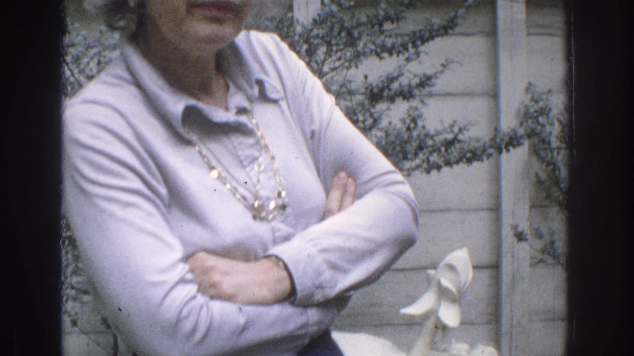 Closer view of a woman in a light blouse standing with arms crossed beside a small white statue.