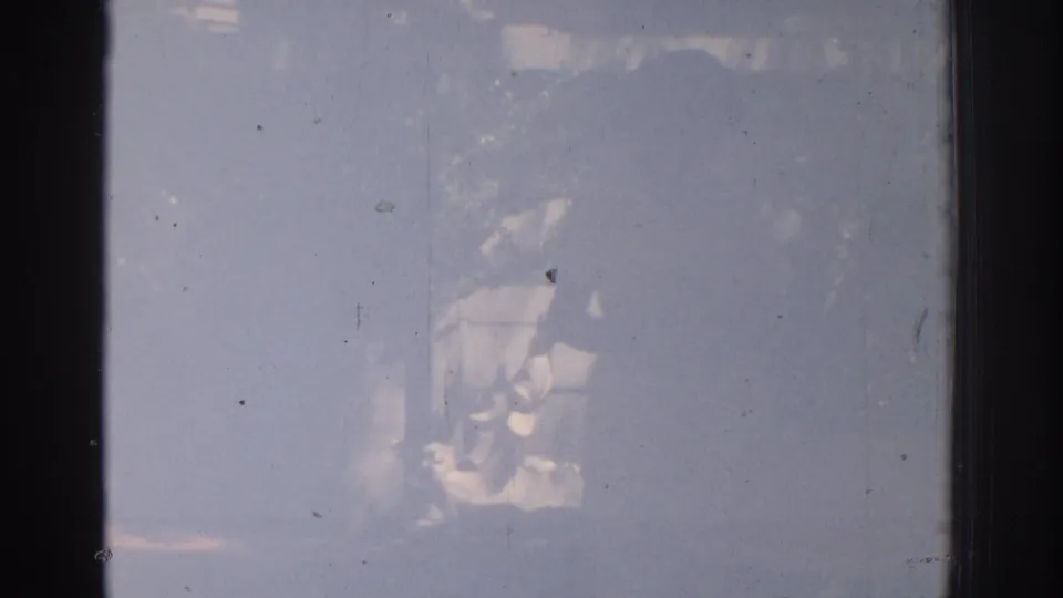 A faded 8mm frame shows a barely visible woman and garden fountain through heavy exposure haze.