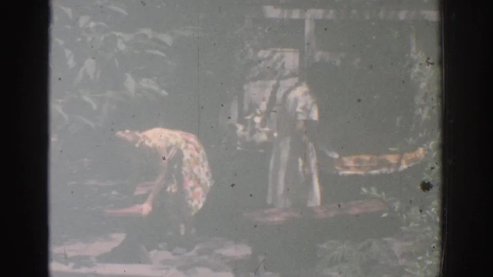 A woman in a floral dress bends to work near plants while another figure and a garden fountain appear in the background.