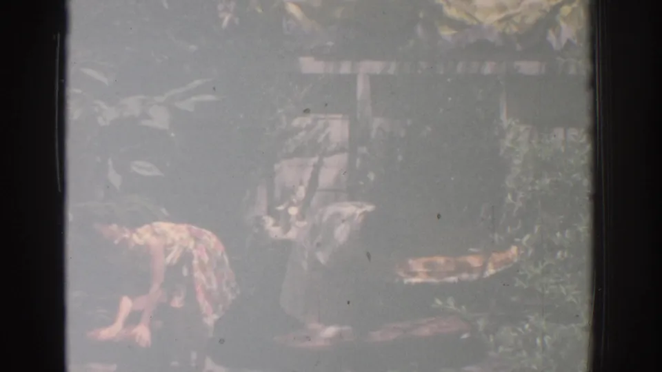1971 Miami garden scene with two women bent toward decorative items, filmed in soft, faded 8mm color.