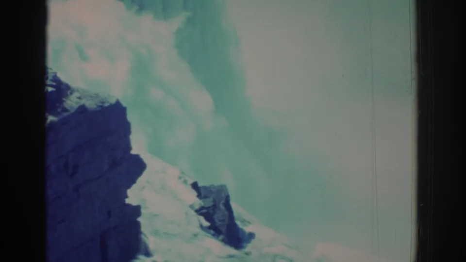 A 1971 8mm tourist view shows Niagara Falls mist, pale rushing water, and a dark rock face with faded color and film grain.