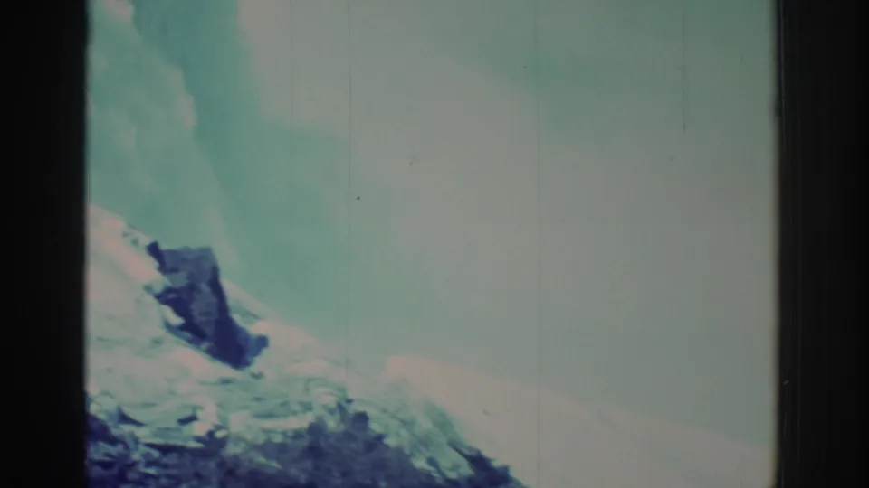 Final 1971 home-movie frame of Niagara Falls with soft teal water, rising mist, a rocky outcrop, frame bars, and aged film marks.