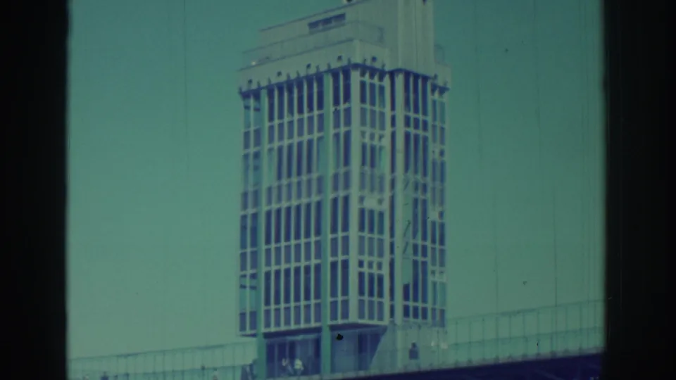 1971 Niagara Falls frame with the tower, bridge railings, small pedestrians, and a teal color cast from aged 8mm film.