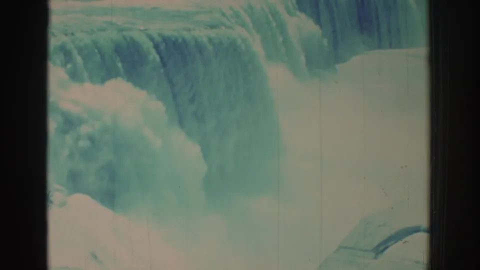 Niagara Falls water pours below the bridge while the upper frame still includes the tower and walkway from the visitor viewpoint.