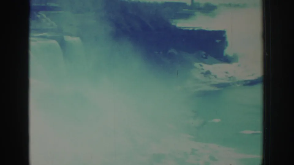 1971 8mm frame at Niagara Falls showing river water, dark gorge edges, and bright spray from the falls.