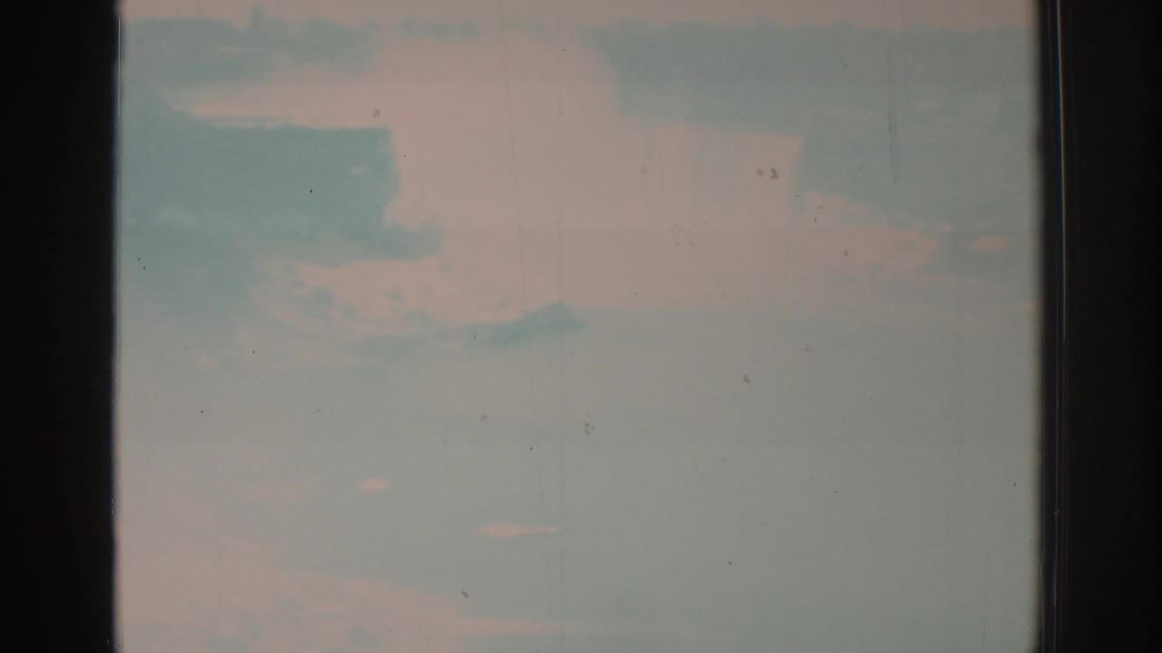 Opening 1971 8mm frame from Niagara Falls footage, with a washed pale sky or misty water area and visible film gate edges.