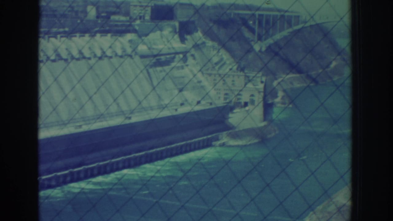 Niagara Falls, New York hydroelectric infrastructure appears behind a diamond safety fence in this blue-green 8mm frame.