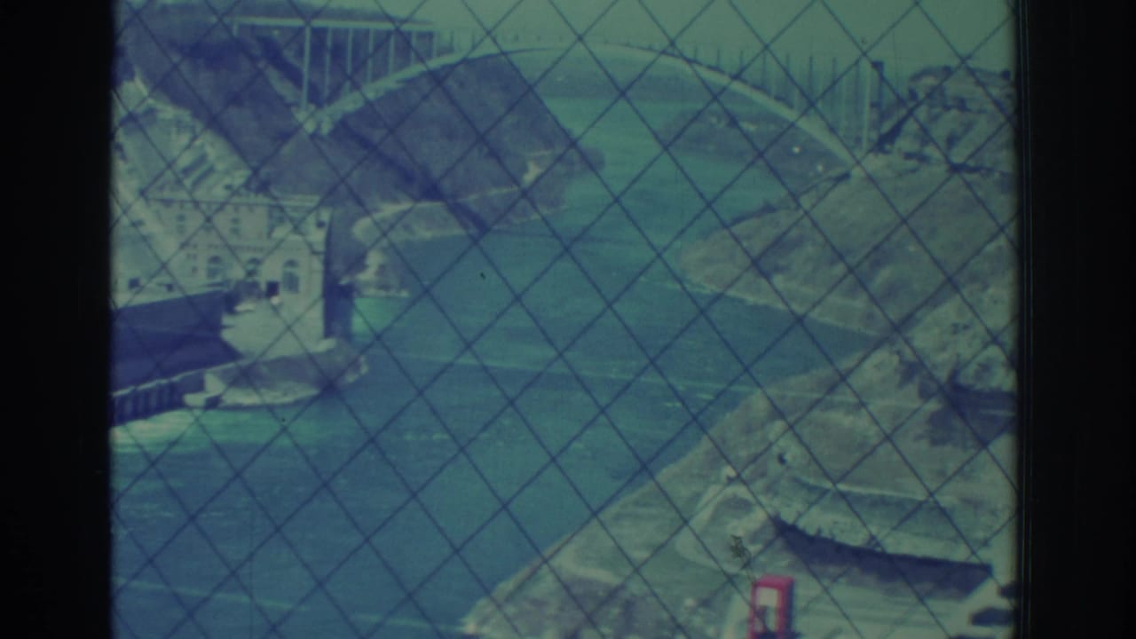 1971 Niagara Falls area dam and river gorge viewed through safety mesh on blue-green 8mm film.