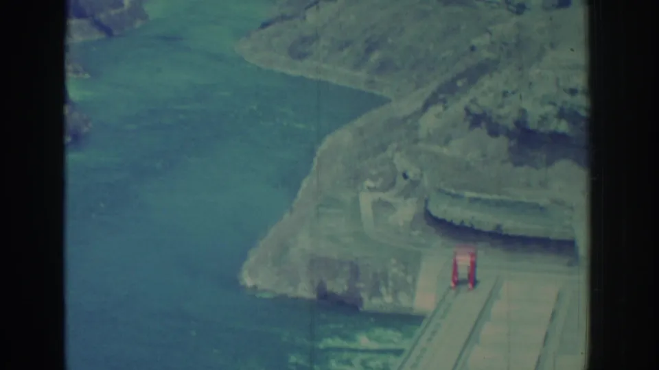 Niagara Falls area river gorge with cliffs and a small red arched bridge, captured on 1971 8mm film.