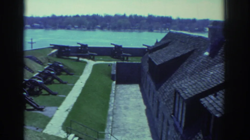 1971 Niagara-area fort scene with cannon rows, stonework, walkways, and a shingled-roof building overlooking the river.