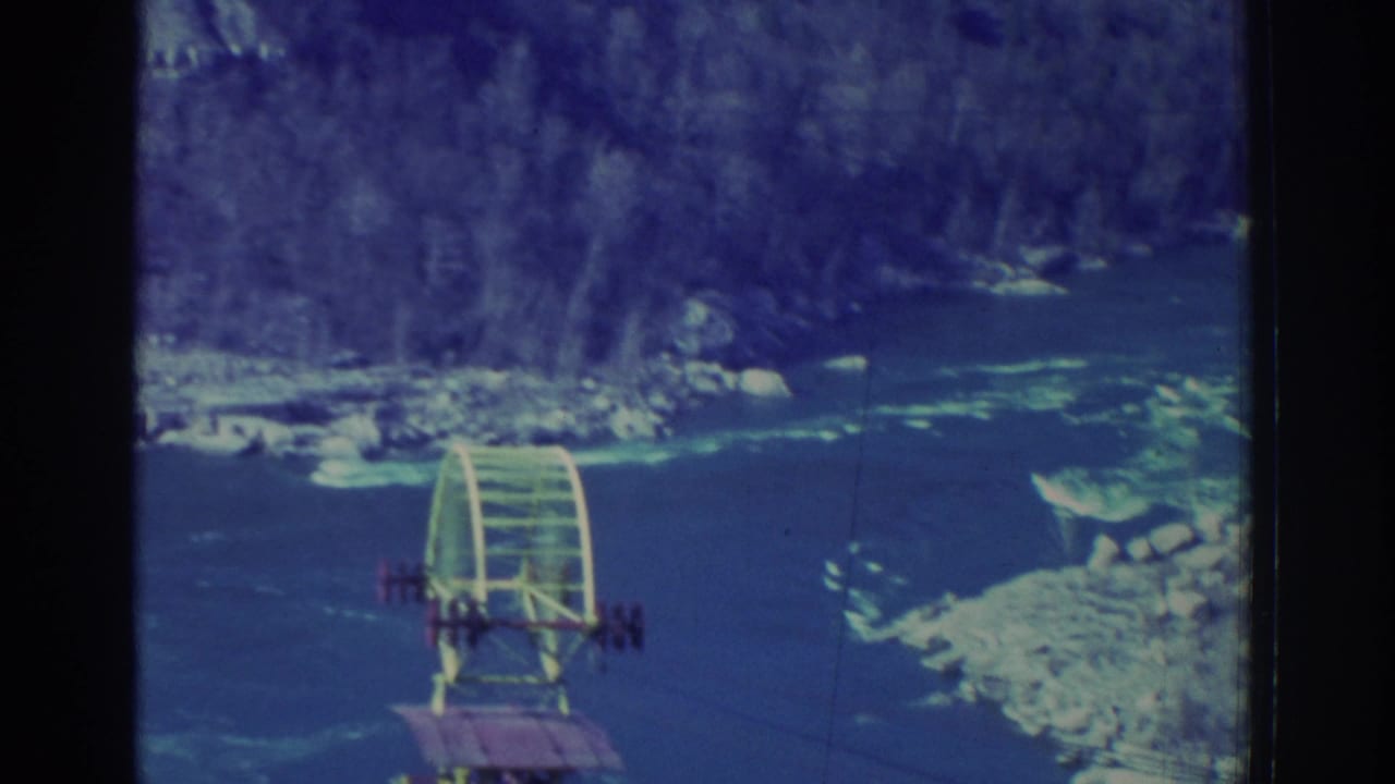 Gondola seen farther across the gorge with river and rocky banks below.