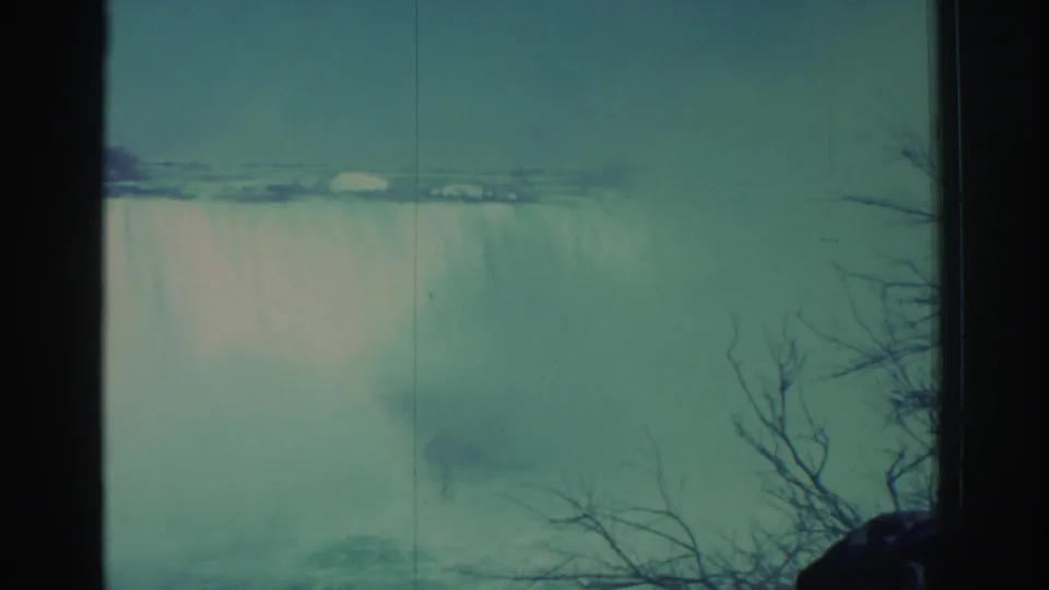 1971 Niagara Falls footage showing a broad curtain of water, drifting mist, teal color cast, and leafless branches near the frame edge.