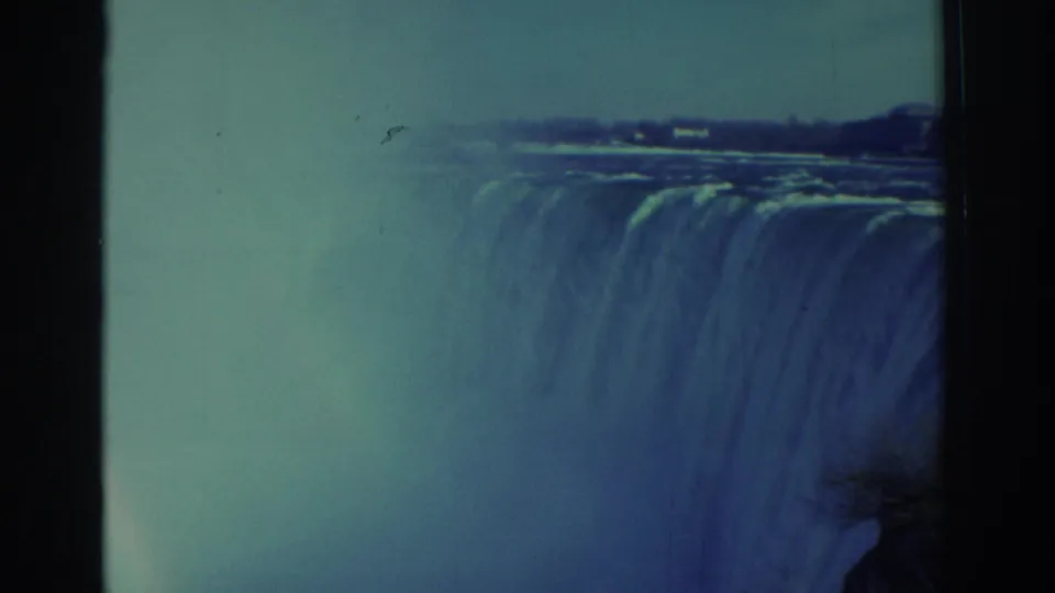 Closer 1971 8mm view of Niagara Falls, emphasizing the water crest, heavy mist, blue-green tint, and film gate edges.