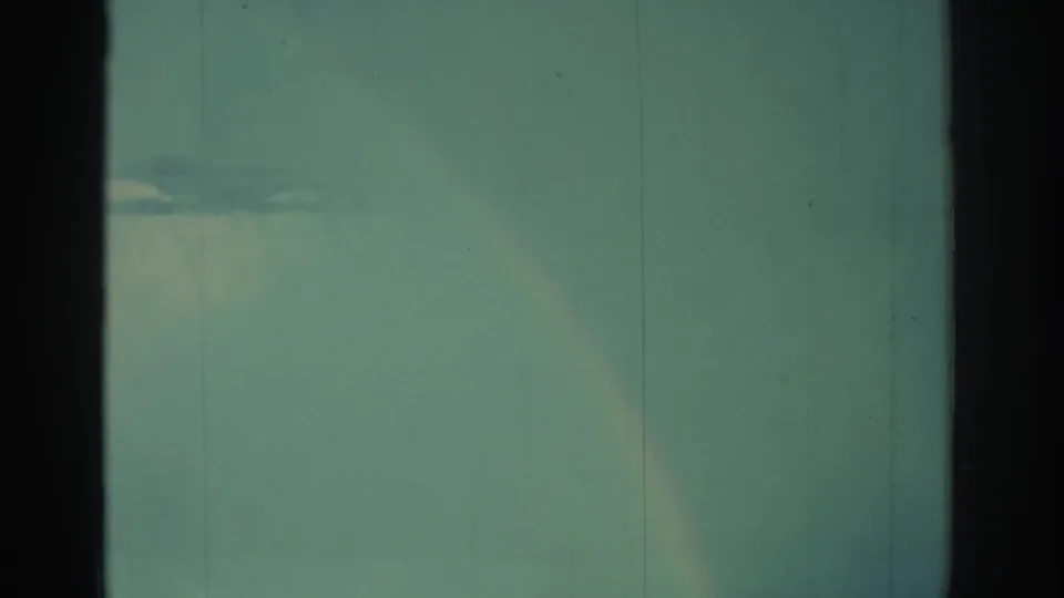1971 8mm view of Niagara Falls with a pale rainbow descending through mist and the waterfall crest visible on the right.
