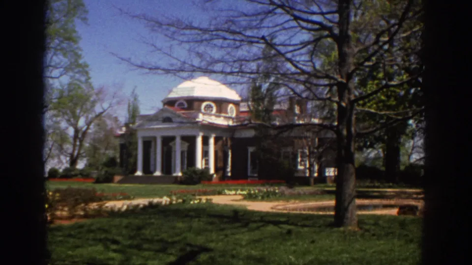 1971 8mm view across shaded Richmond grounds toward a domed civic building with white columns and brick walls.