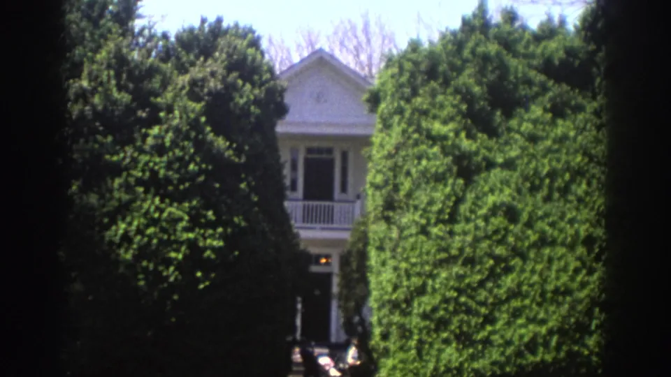 1971 Richmond residential exterior framed by manicured hedges, with the porch and doorway partly visible.