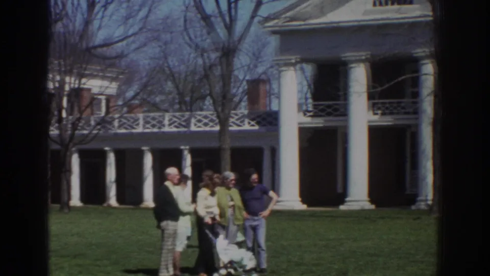 1971 Richmond-area frame showing visitors paused in conversation near a stroller, with mansion columns and porch behind them.