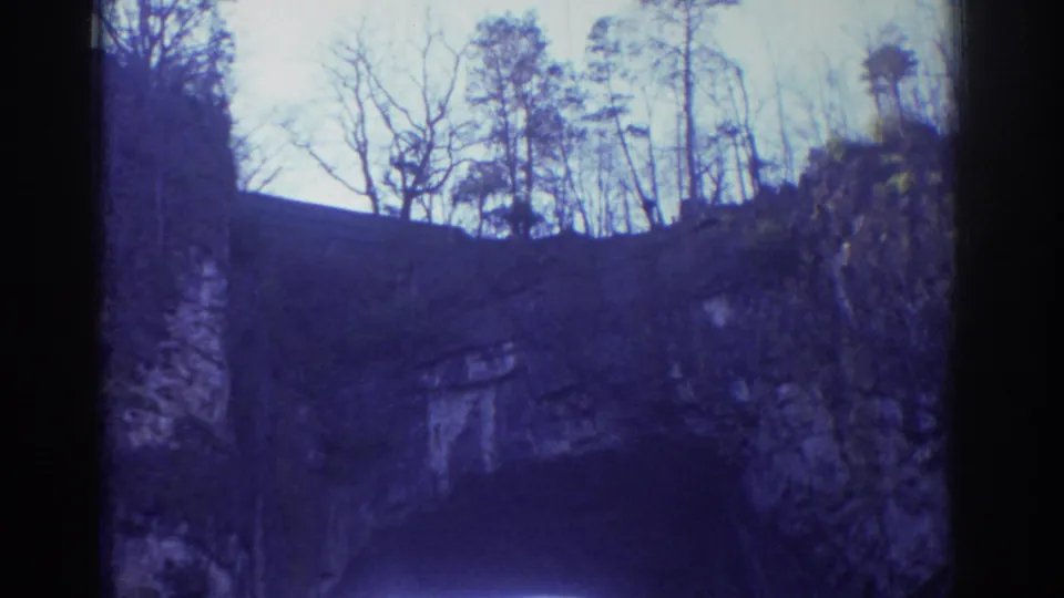 Handheld 8mm view of the Richmond rock formation, with dark stone, pale sky, and winter trees along the top edge.