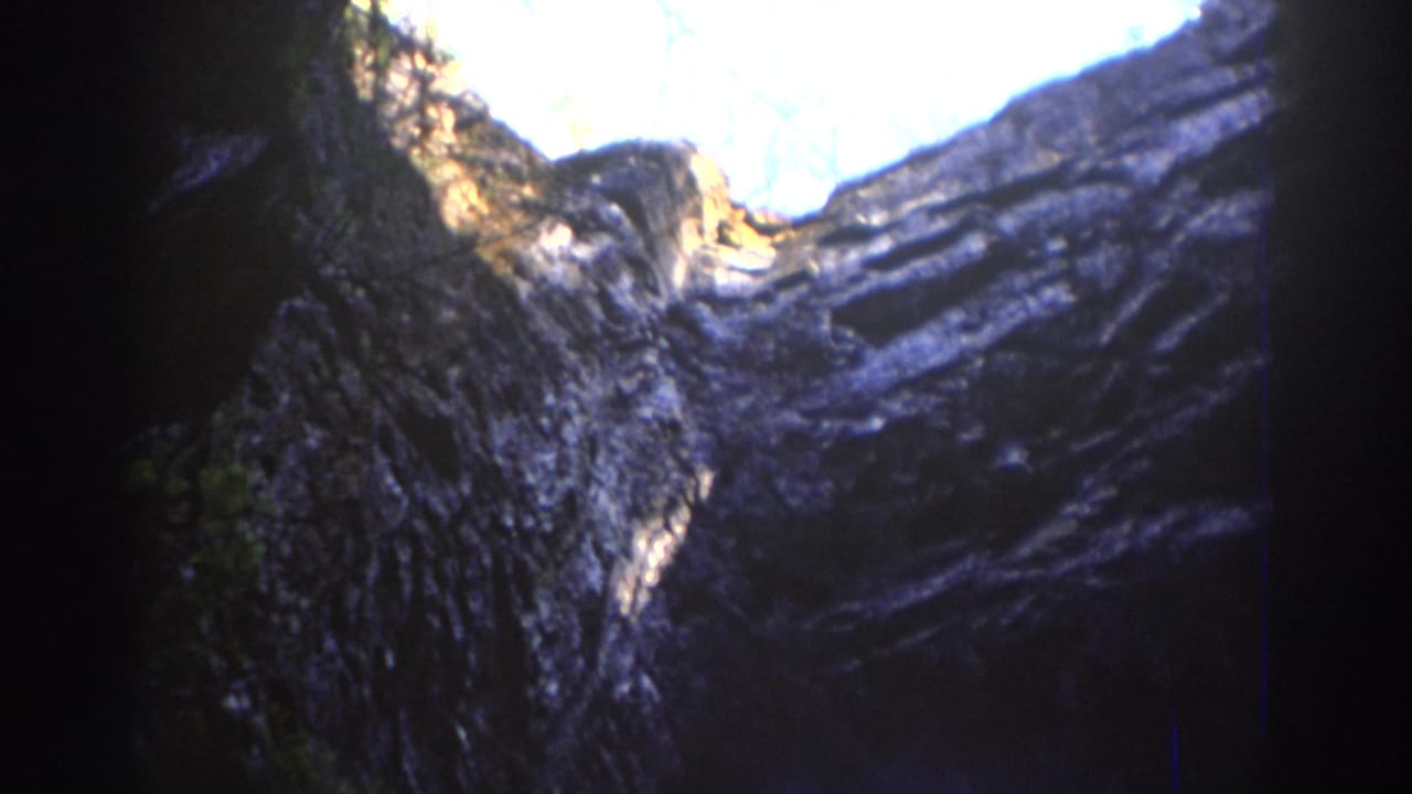 Layered rock walls rise toward a bright sky opening above.