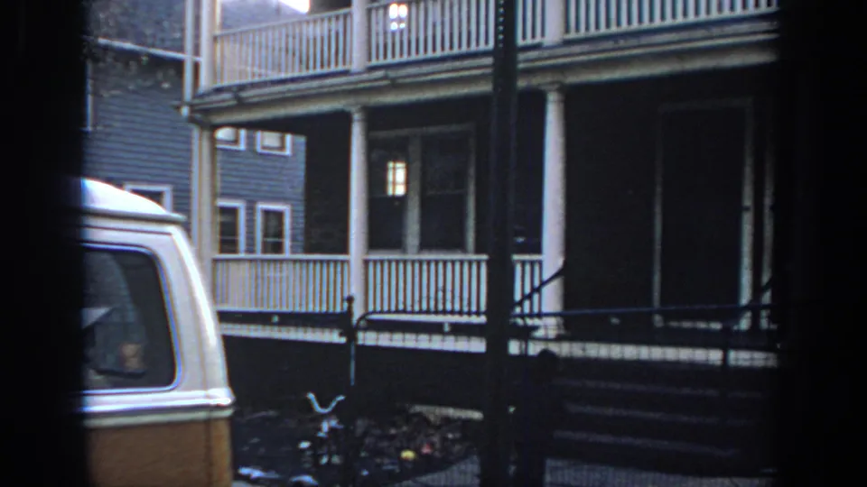 Residential Philadelphia exterior with porch railings, a bicycle near the fence, and a cropped two-tone van.