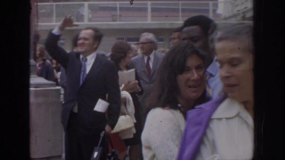 1972 Philadelphia crowd frame with a suited man waving and women passing close to the handheld camera.
