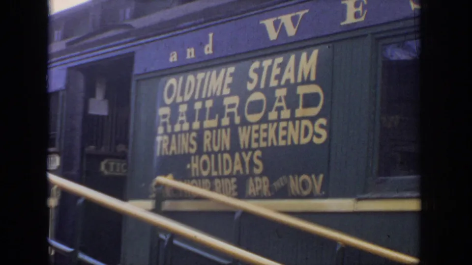 Dark green-blue railcar side with gold lettering advertising old time steam railroad weekend and holiday excursions.