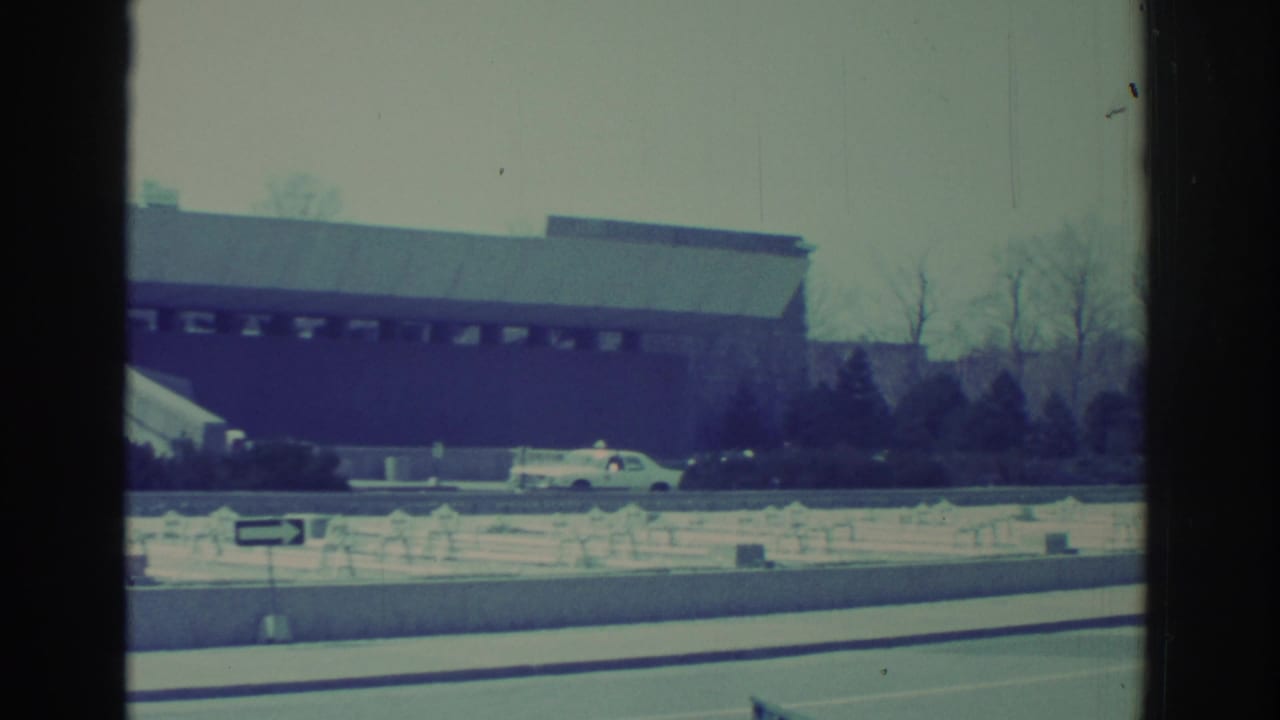 Low exterior building across a road with snowbanks and parked cars.