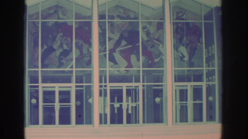 Close exterior view in Toronto showing the Hockey Hall of Fame glass entry and a large mural of hockey players above the doors.