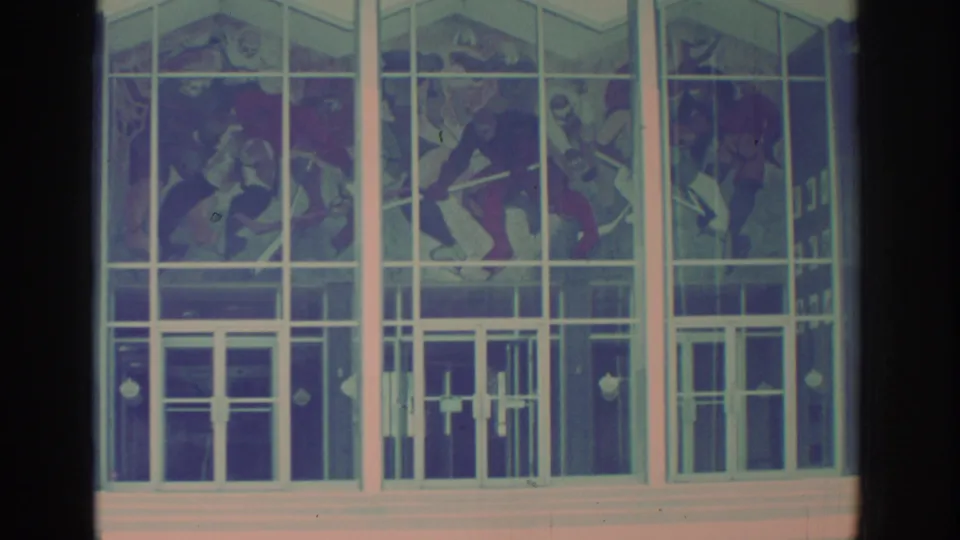 1972 Toronto 8mm frame showing a modern glass facade with white mullions and stained glass figures above a public entrance.