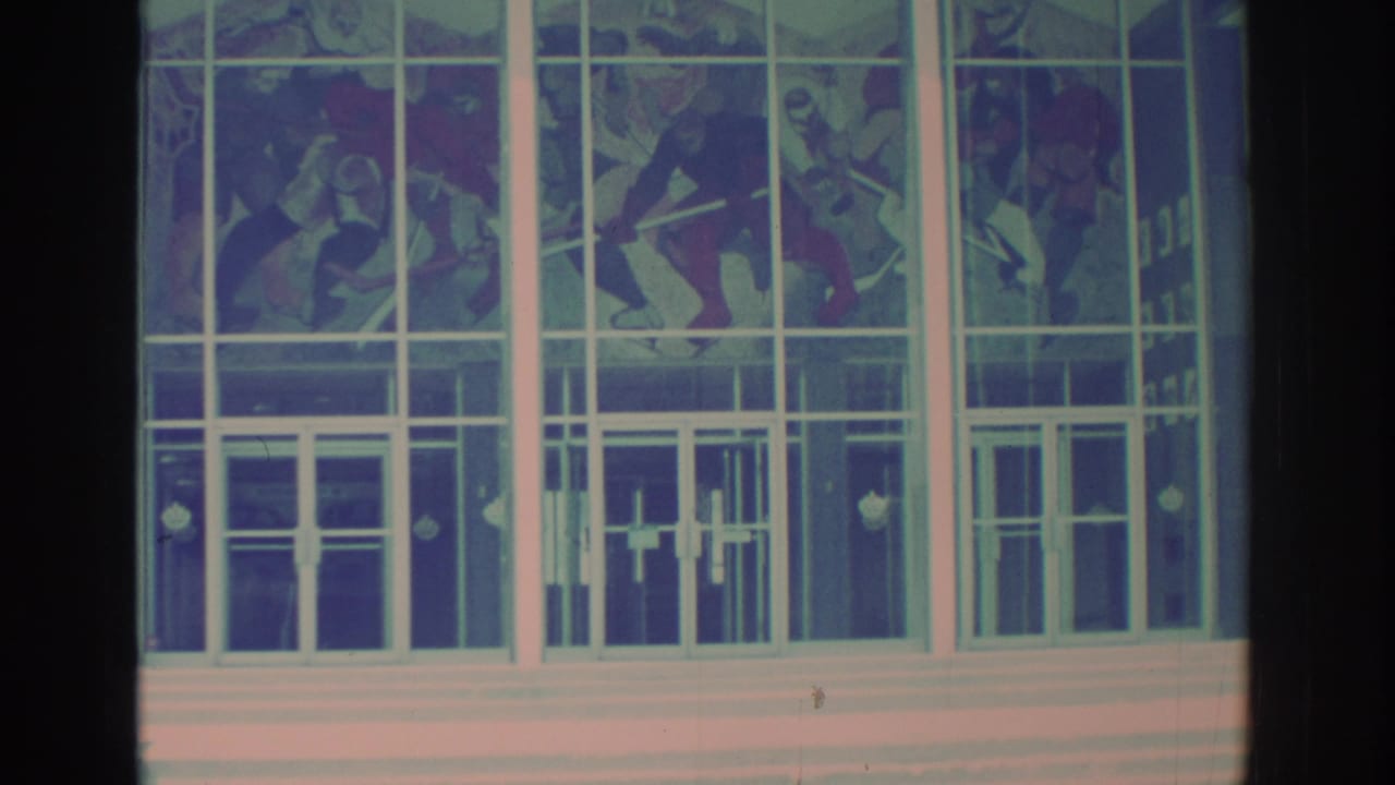Toronto 8mm view of stained glass artwork set into a broad white-framed entrance facade, with film vignetting at the edges.