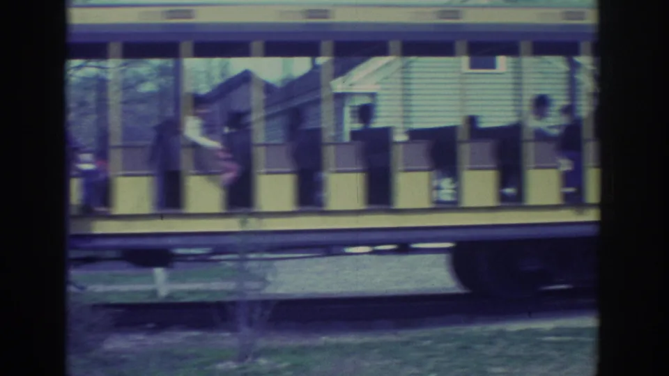 Open-sided tram rolls by as a horse-drawn carriage with dark horses appears briefly in the background.