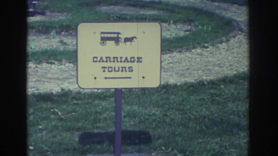 A yellow Carriage Tours sign with a small carriage-and-horse icon stands in grass, framed by 8mm film edges and mild color fading.