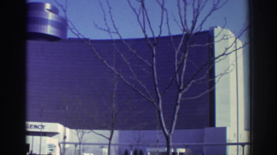 1972 Toronto home-movie frame of bare trees in front of the Hyatt Regency curved facade and partial sign.