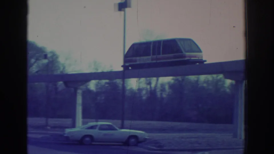 1972 Toronto frame showing the elevated transit car on its guideway with a period car and trees below.
