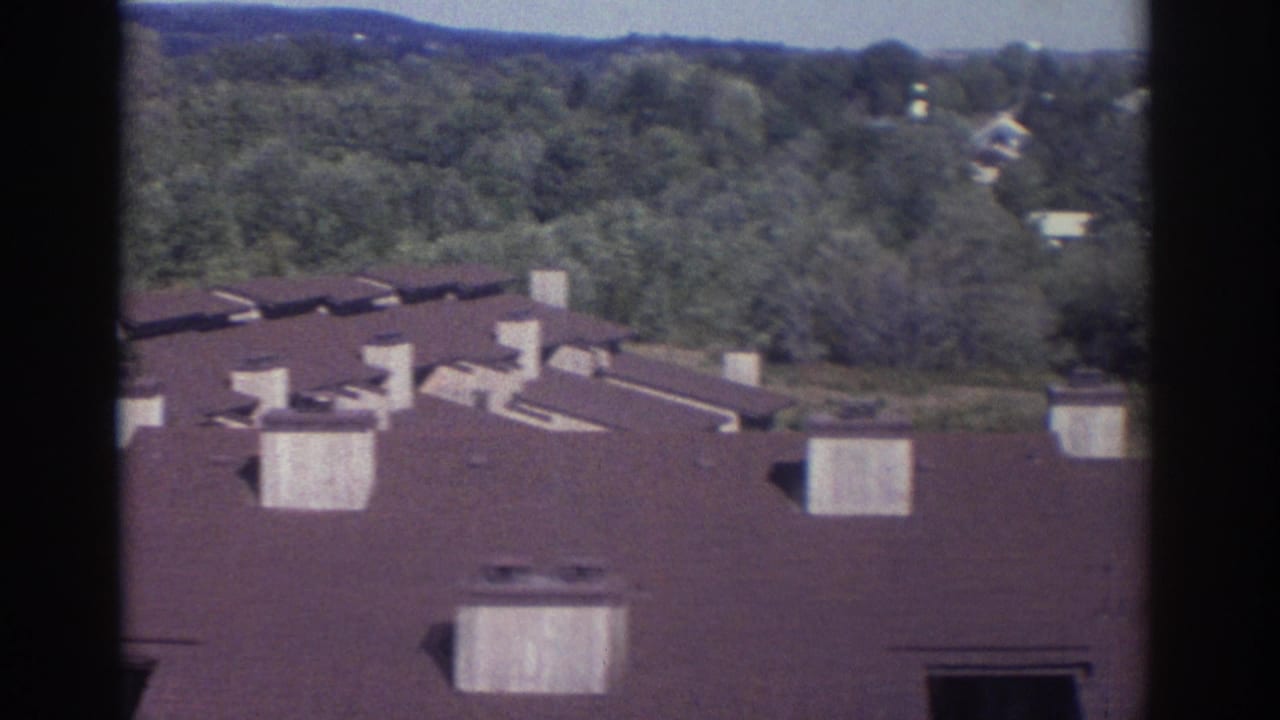 1972 Toronto home-movie view of residential rooftops, chimneys, trees, and distant houses from an elevated window.