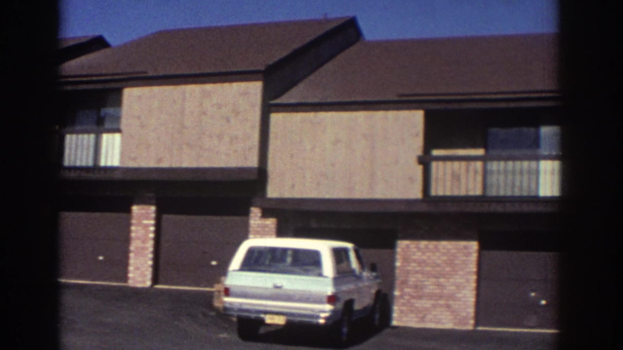 1972 Toronto 8mm frame showing a residential building exterior with balcony, double garage, and a light station wagon in the driveway.