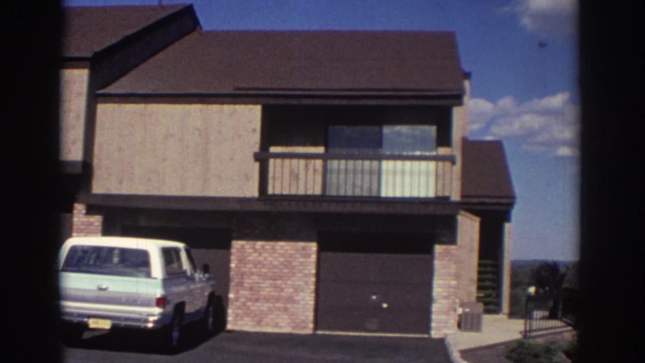 Residential building exterior with station wagon, balcony, garage doors, and brick columns.