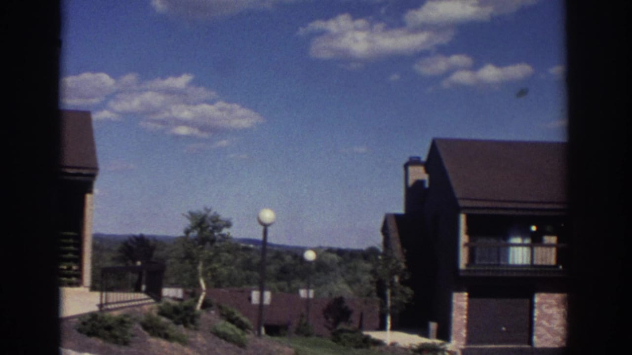 Low-rise residential buildings with balconies under a blue sky with scattered clouds.